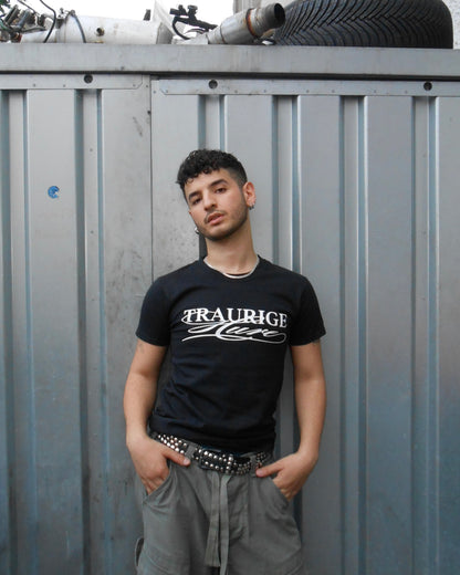 Baran Kok trägt das schwarze „Traurige Hure“ T-Shirt aus dem offiziellen Baran Kok Merch Shop